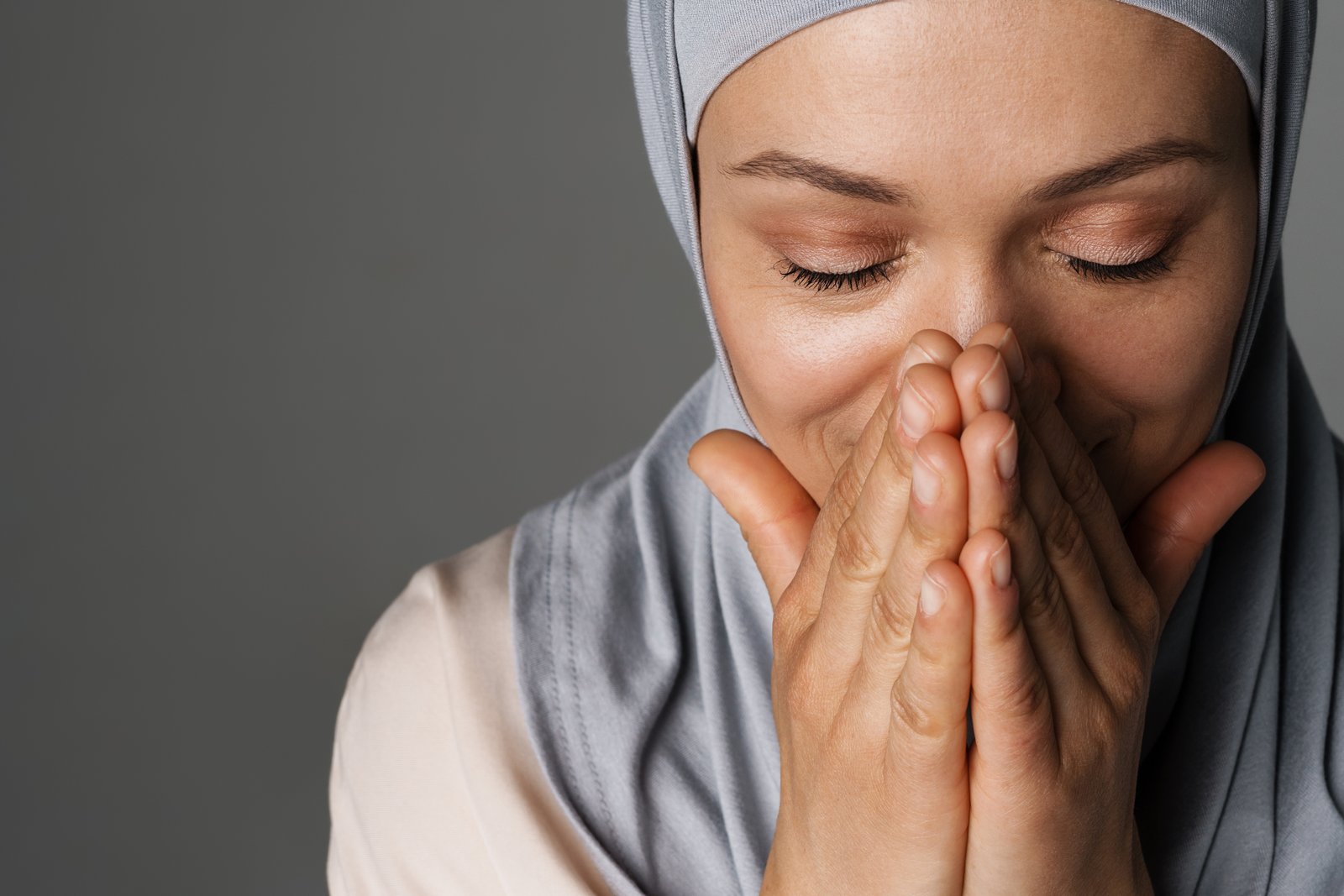 Middle eastern woman in hijab smiling while covering her mouth