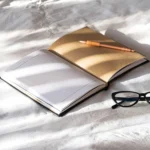 open-notebook-pen-and-eyeglasses-on-white