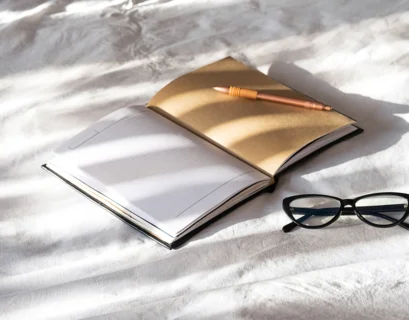 open-notebook-pen-and-eyeglasses-on-white